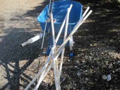 white pvc pipe leaning up against a blue wheelbarrow